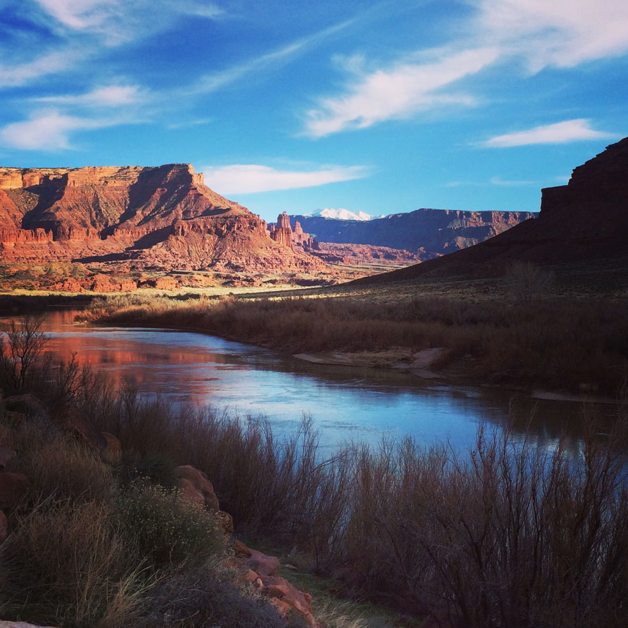 A red rock canyon with a calm river winding through it