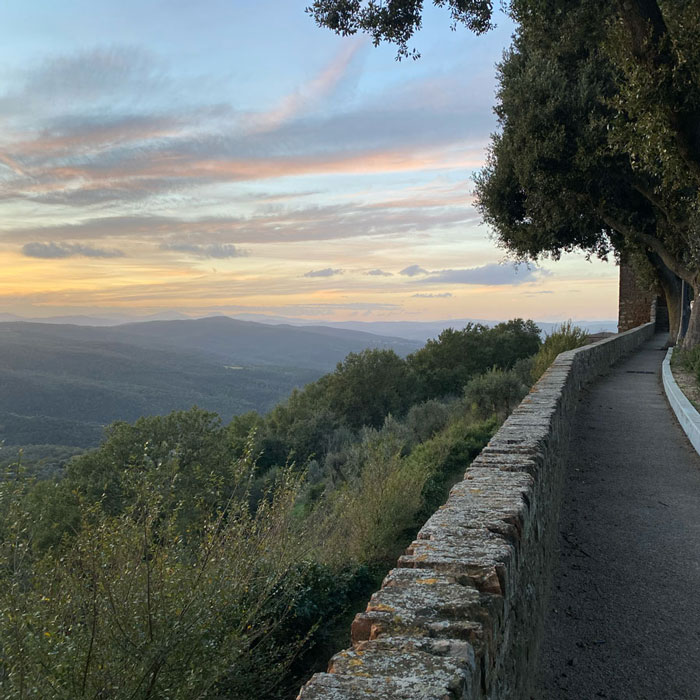 A stone-walled path along a hillside overlook at sunset