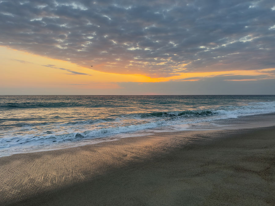 Ocean waves at sunset beneath a glowing sky